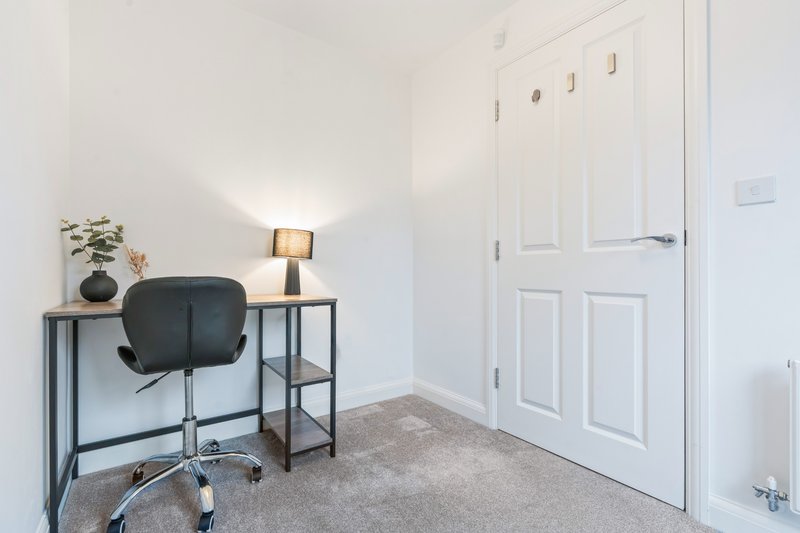 Bright bedroom workspace with desk, black office chair, lamp and storage shelving