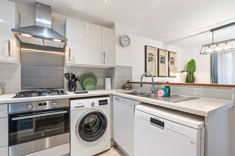 Modern kitchen with white cabinetry, stainless steel appliances, gas hob, and grey tile backsplash