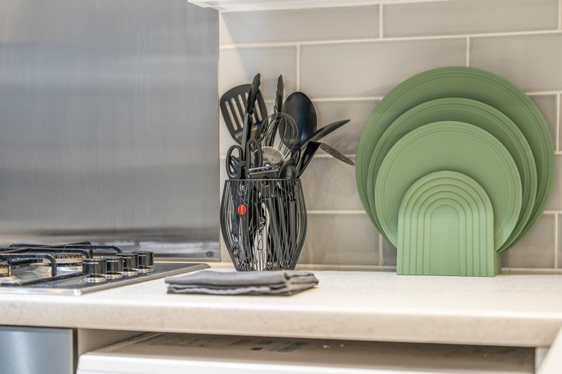Kitchen countertop with utensil holder, stacked green bowls, and stovetop visible