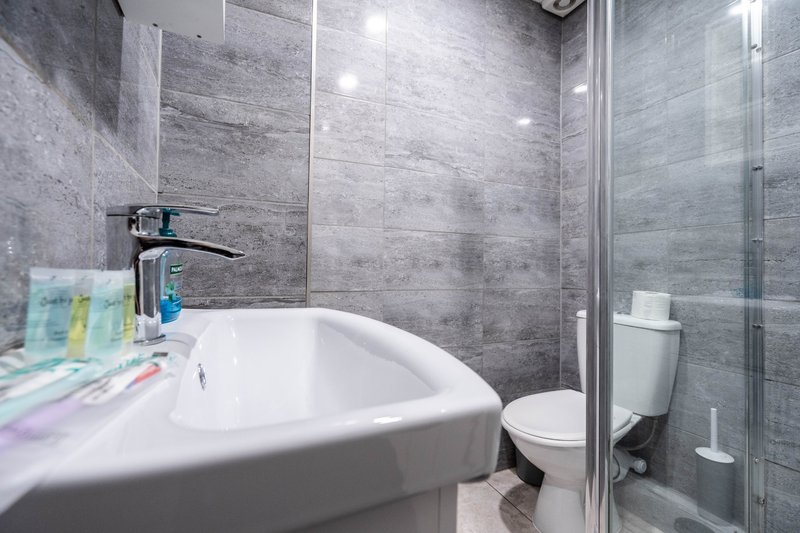 Modern bathroom with white basin, grey tile walls, shower enclosure and toilet
