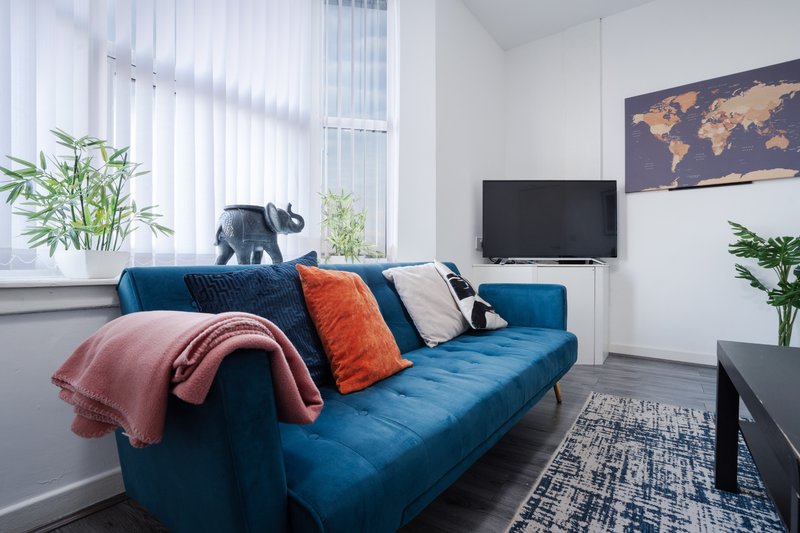 Modern living room with blue sofa, colorful cushions, TV, and world map wall art