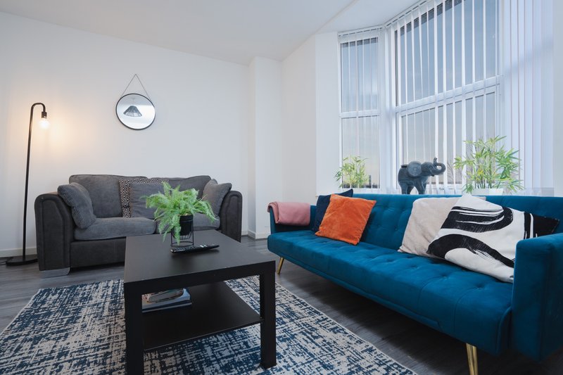 Modern living room with gray sofa, blue couch, black coffee table and floor lamp