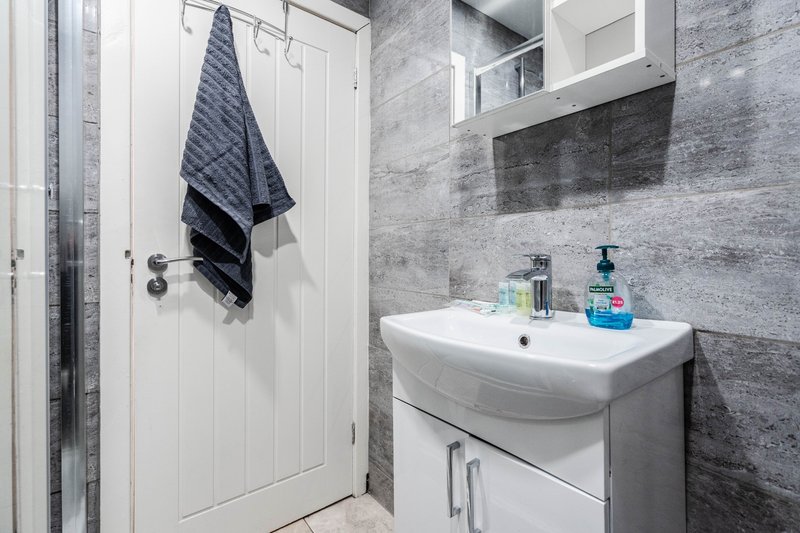 Modern bathroom with white sink, gray tile walls, mirror and towel rack