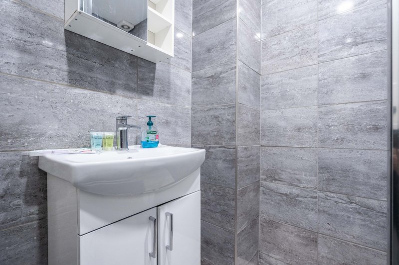 Modern bathroom with white vanity sink, gray tile walls and mirror cabinet
