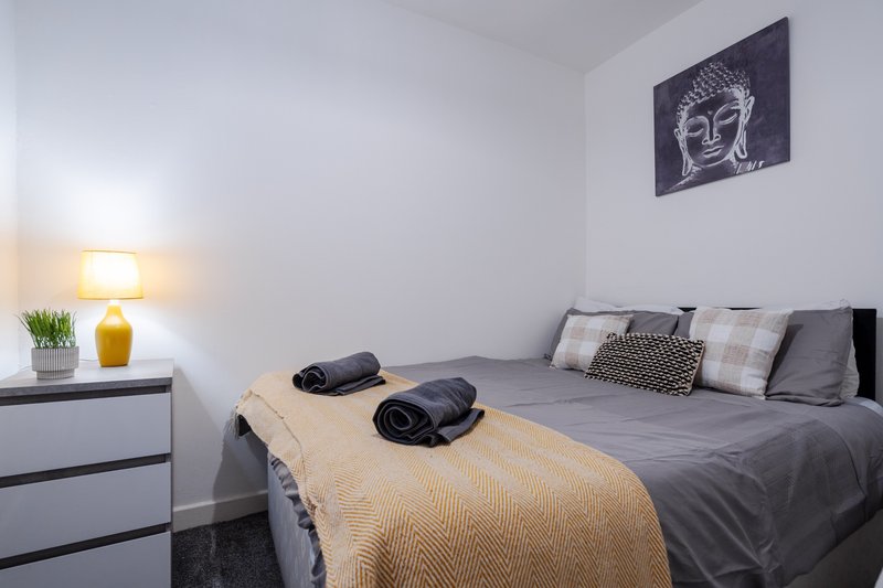 Modern bedroom with double bed, grey bedding, decorative pillows and throw blanket