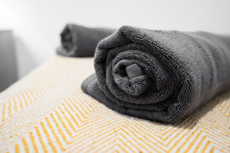 Rolled dark gray towels on yellow and white patterned bedding
