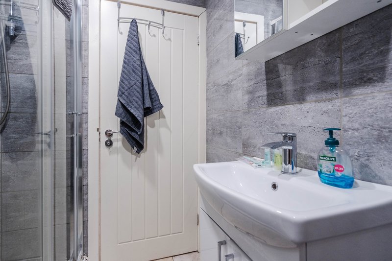 Modern bathroom with white sink, gray tile walls, shower enclosure and towel rack