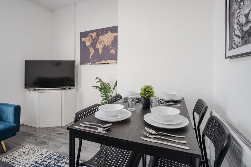 Dining area with black table, place settings, plants, TV and world map wall art