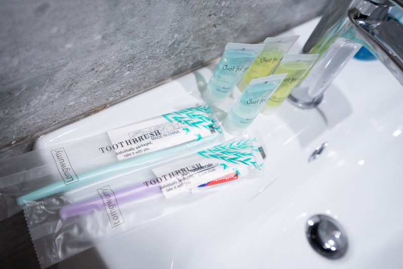 Bathroom sink with toothbrushes, toothpaste tubes, and toiletries arranged on white surface
