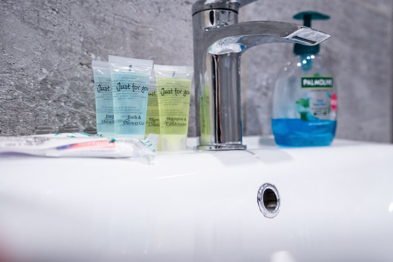Bathroom sink with chrome faucet, hand soap dispensers, and toiletries