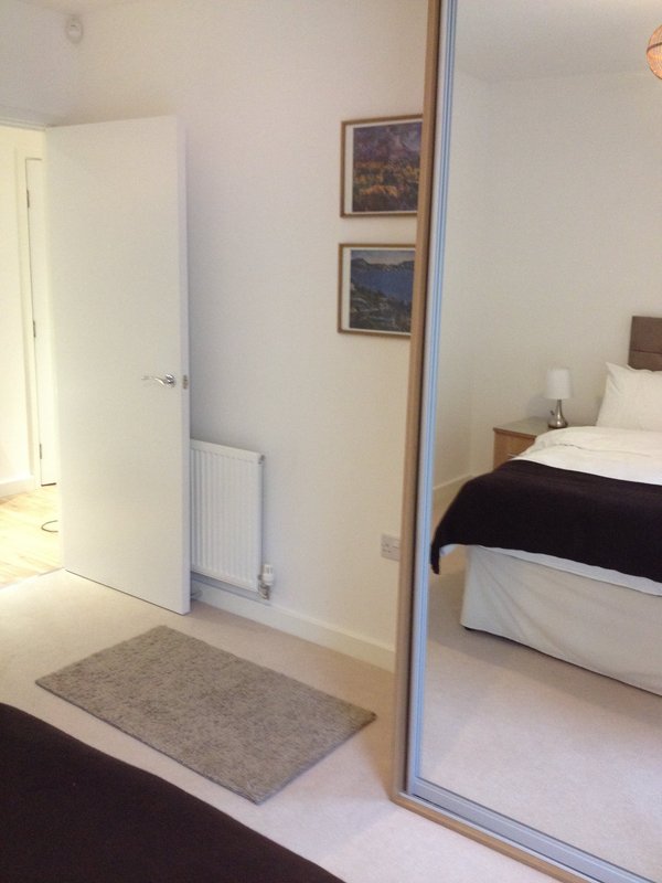 Bedroom with double bed, mirrored wardrobe door, radiator and framed wall art