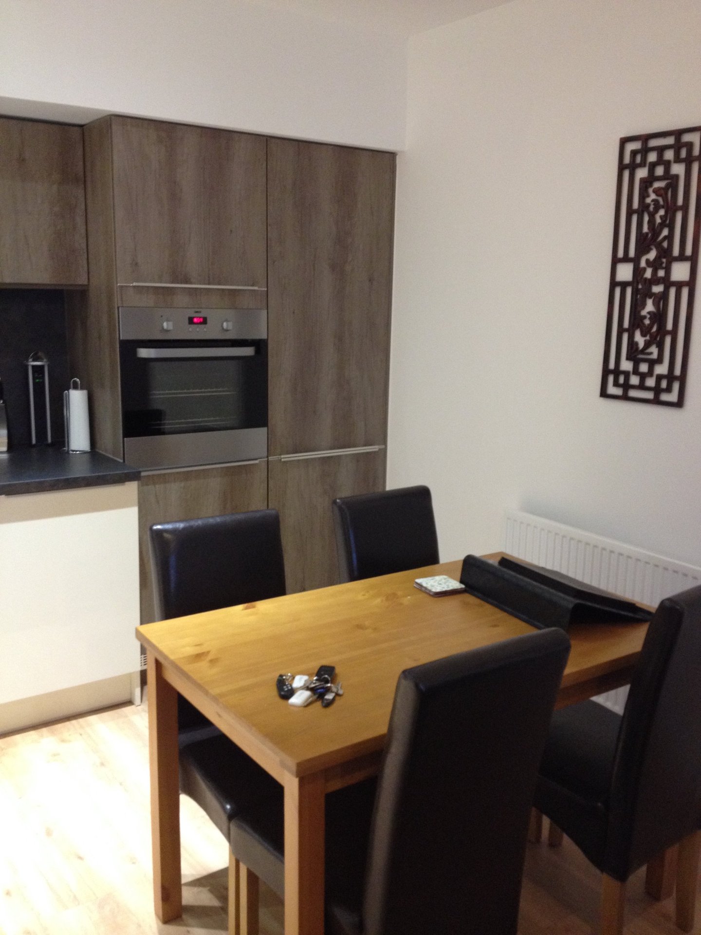 Modern kitchen and dining area with wooden table, black chairs, and built-in oven