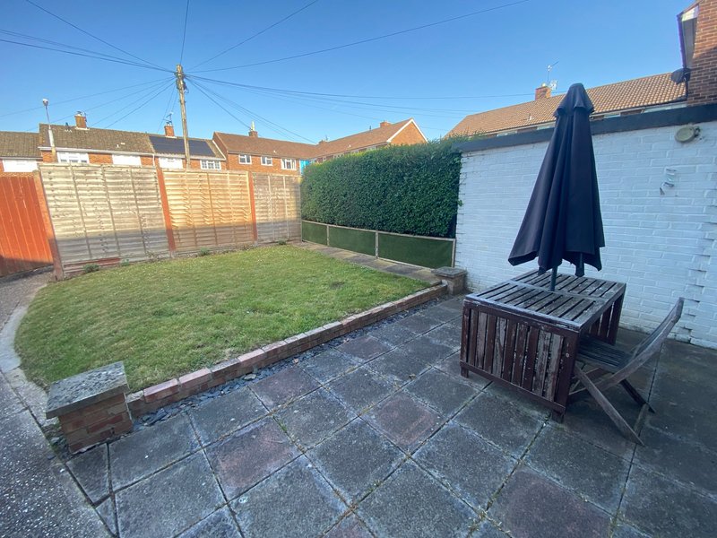 Residential garden with patio, lawn, fencing, and outdoor seating area