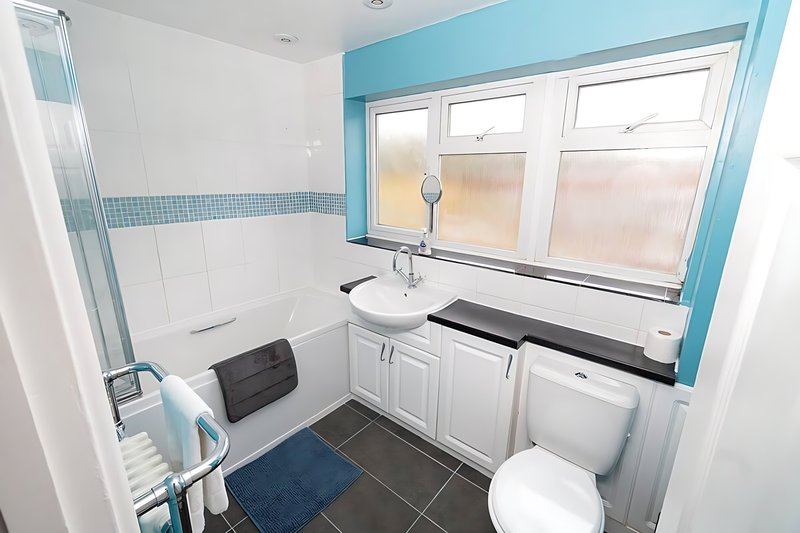 Bathroom with white vanity, toilet, shower over bath