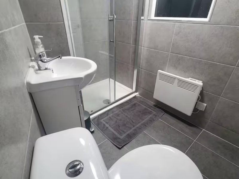 Modern bathroom with toilet, sink, shower enclosure and heated towel rail