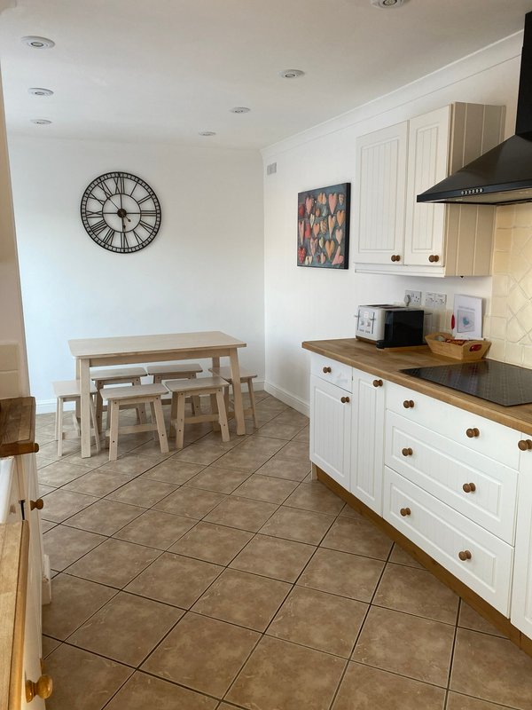 Kitchen with white cabinetry, wooden dining table
