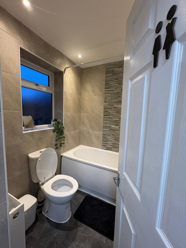 Modern bathroom with toilet, bath tub, tiled walls and window