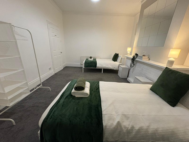 Shared bedroom with two single beds, dark carpet, white walls and wardrobe storage