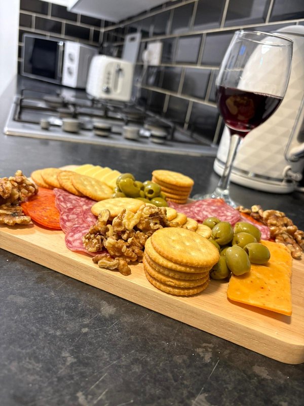Kitchen counter with charcuterie board, wine glass, and appliances in background