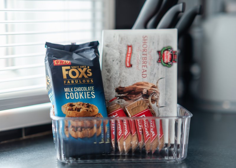 Kitchen counter with clear container holding packaged food items and branded boxes
