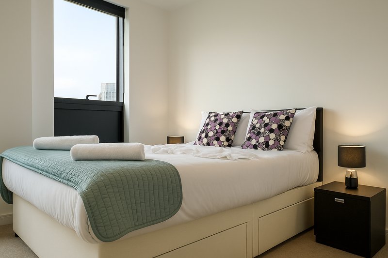 Modern bedroom with double bed, decorative pillows, bedside lamp and window