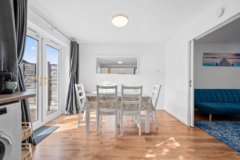Open-plan dining and living space with wooden floor, dining table, chairs and blue sofa