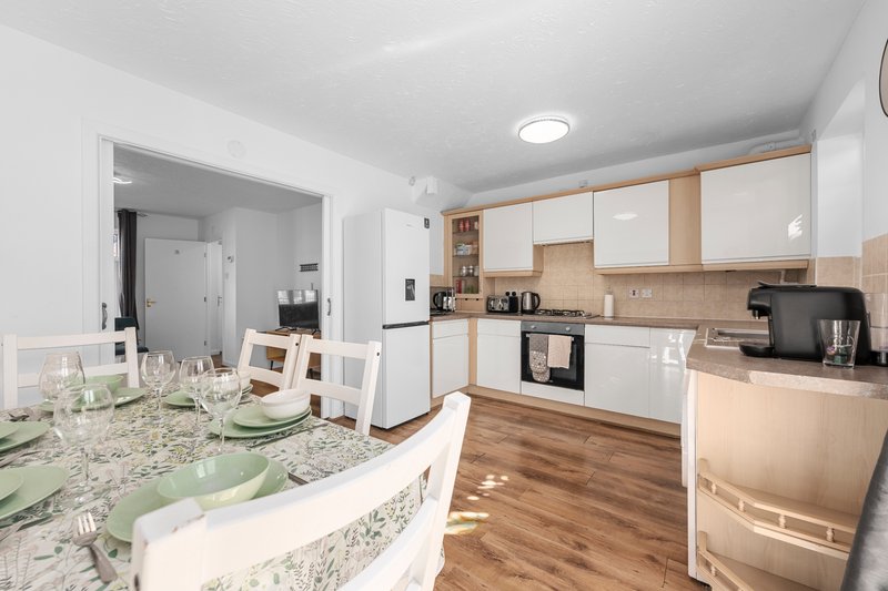Modern kitchen with white and wood cabinetry, granite countertop, and wooden flooring throughout