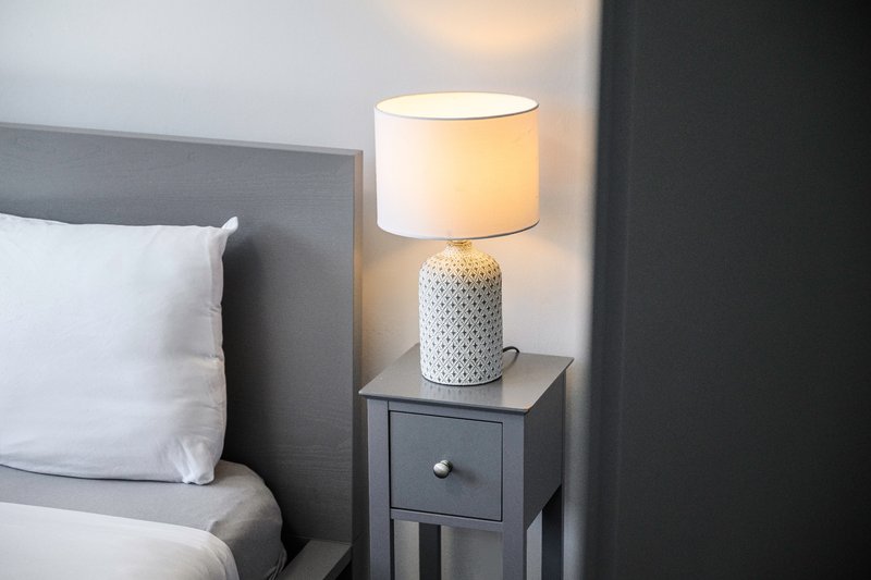Bedroom bedside table with textured ceramic lamp and white shade