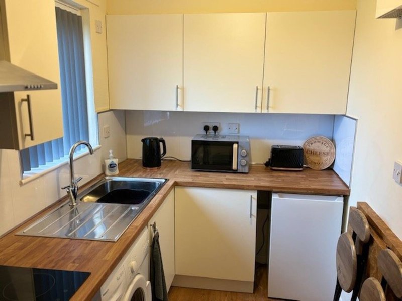 Small kitchen with cream cabinetry, wooden worktops, sink, microwave, kettle and appliances