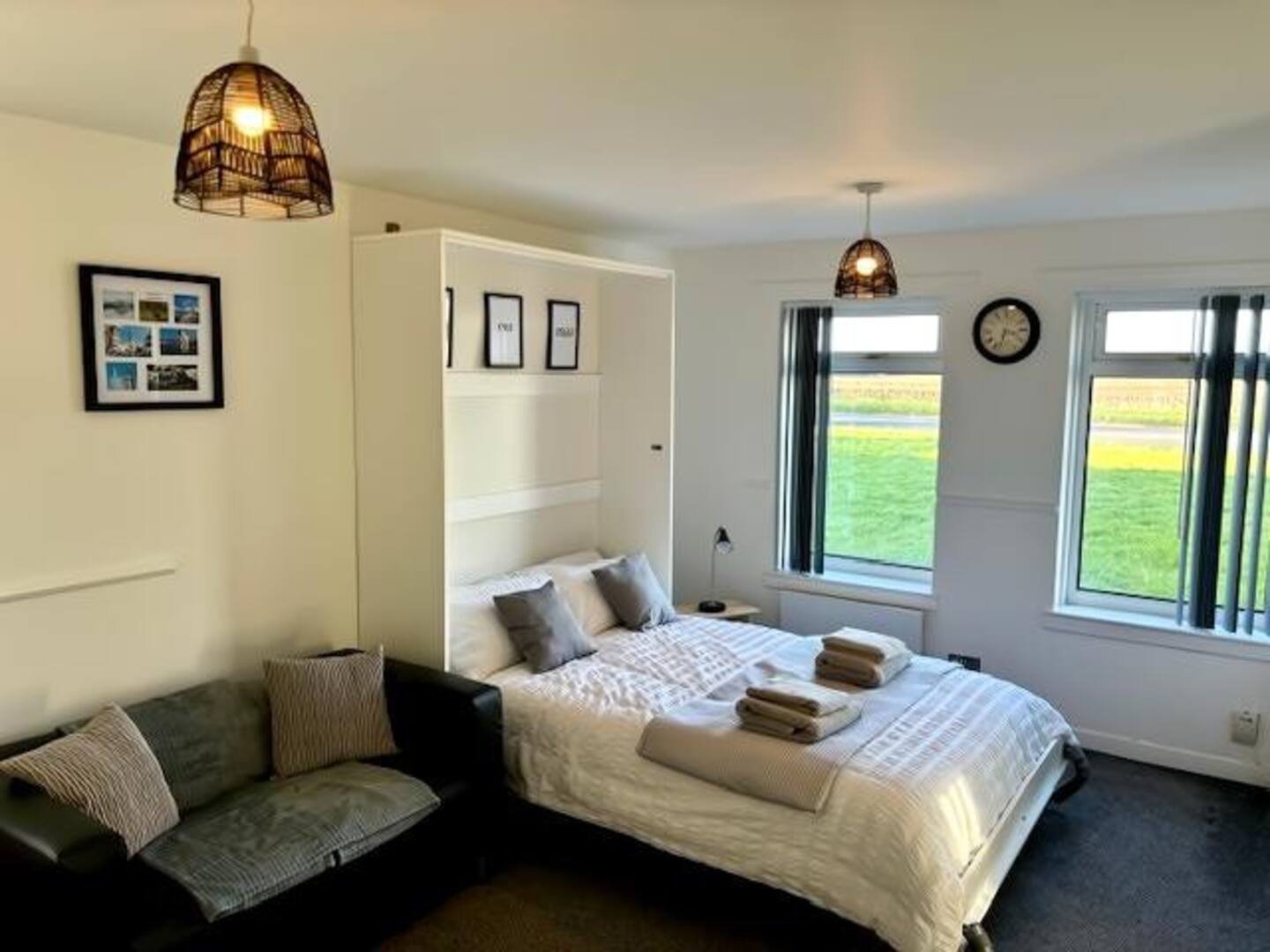 Bright bedroom with double bed, seating area, pendant lights and garden views