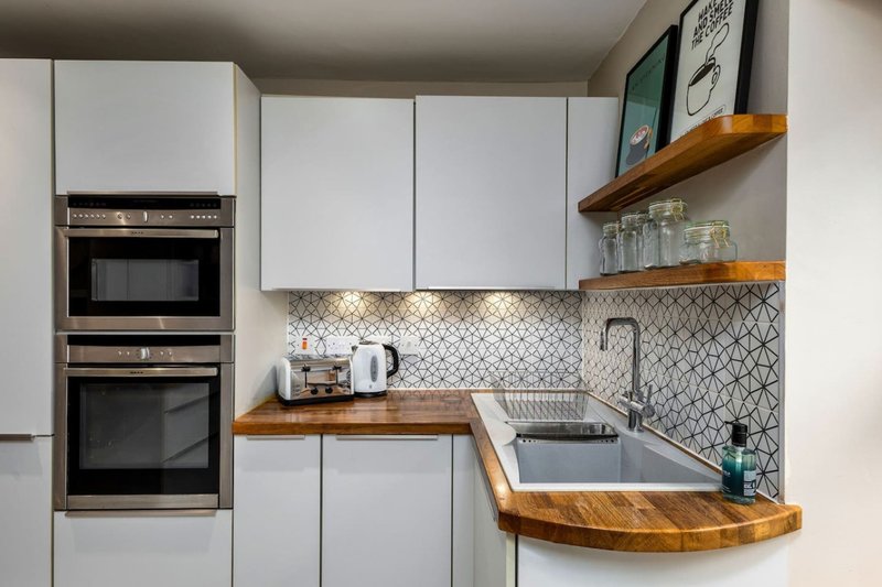 Modern kitchen with white cabinets, wooden countertops, stainless steel appliances and sink