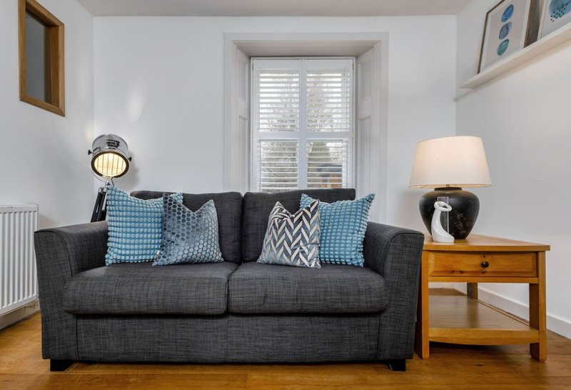 Living room with grey sofa, blue patterned cushions, wooden side table, and floor lamp