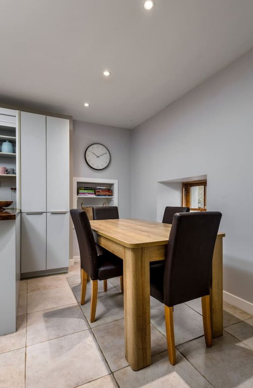 Modern dining room with wooden table, black chairs, wall clock and built-in storage