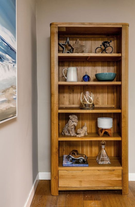 Wooden shelving unit with decorative items including star ornament, white pitcher, blue bowl, glass vase, and figurines