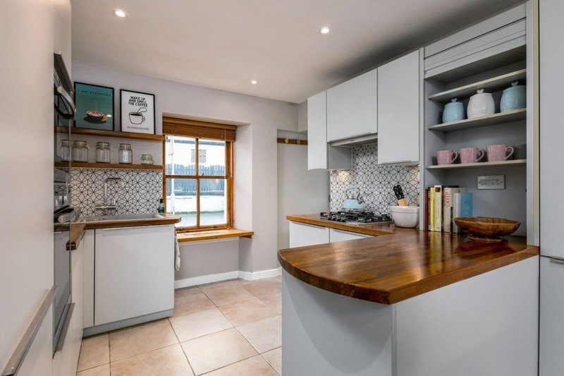 Modern kitchen with white cabinetry, wooden worktop island, open shelving and geometric tile backsplash