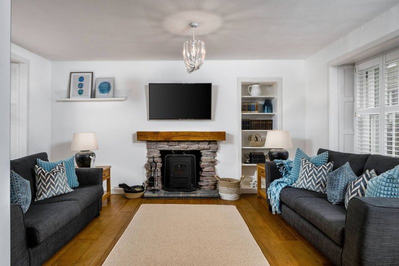 Bright living room with two dark sofas, fireplace, wall-mounted TV and blue accent cushions