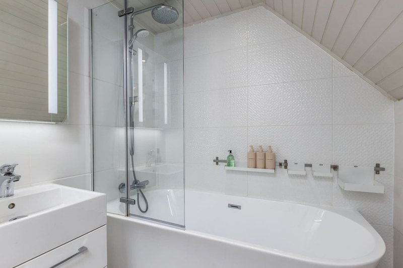 Modern bathroom with white freestanding bathtub, glass shower screen and wall-mounted sink