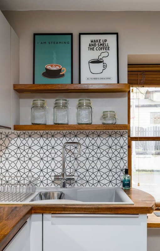 Kitchen with wooden shelves, glass jars, framed coffee-themed wall art and patterned backsplash