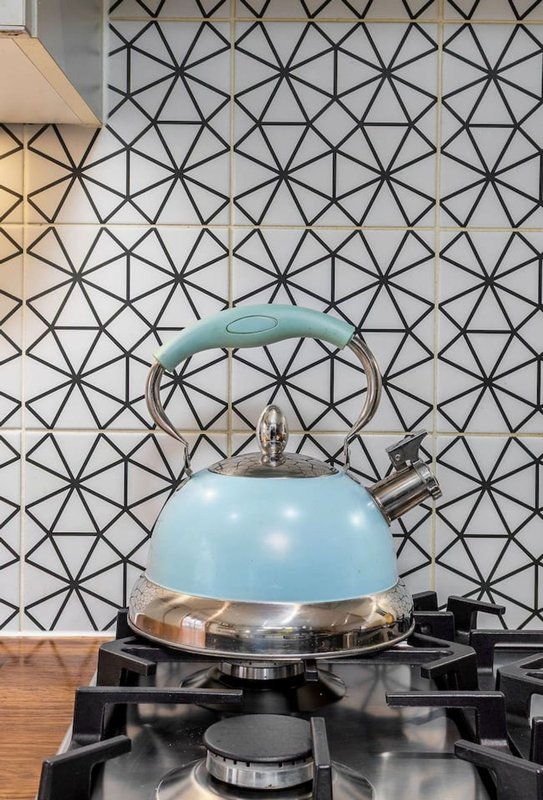 Blue kettle on stovetop with geometric patterned backsplash