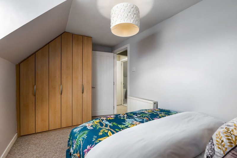Bright bedroom with double bed, wooden wardrobe, textured ceiling lamp, and carpeted floor