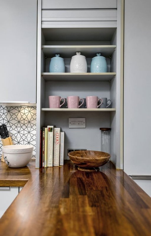 Kitchen counter with open shelving displaying ceramic jars, books, and decorative bowls