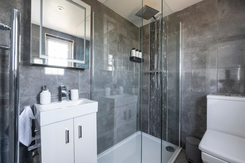 Modern bathroom with walk-in shower, white vanity unit, mirror and toilet
