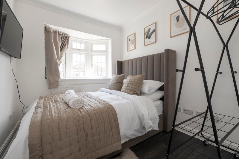Modern bedroom with double bed, grey headboard, white bedding, and large window