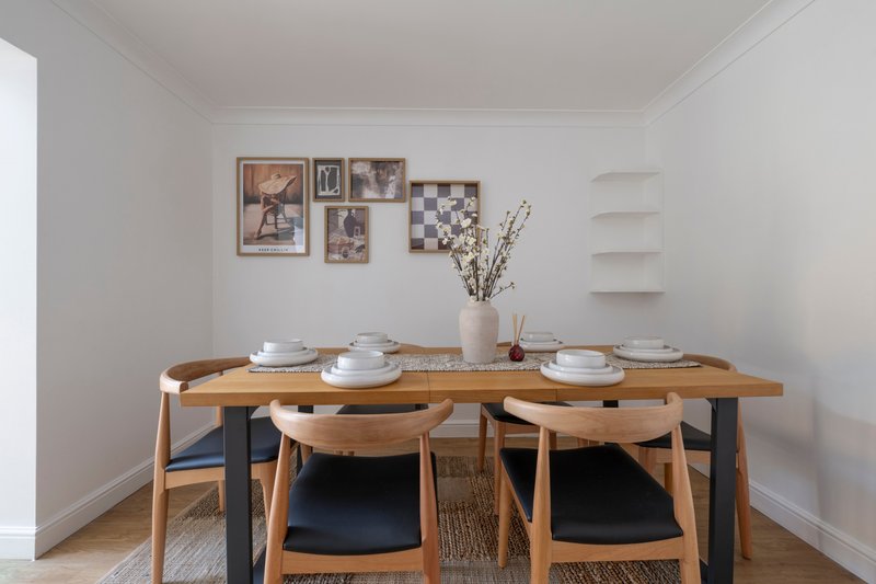 Dining room with wooden table, chairs, place settings, and wall art