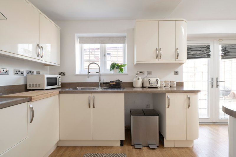 Modern cream kitchen with white cabinetry, brown countertops, sink, and stainless steel appliances