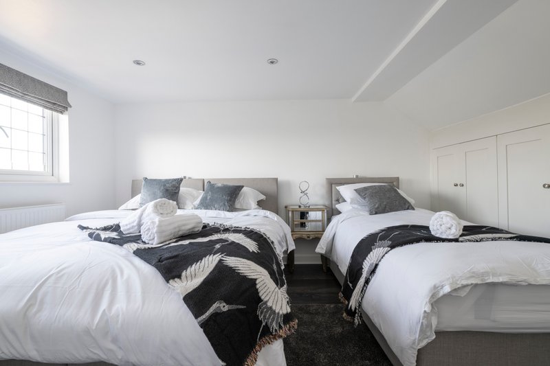 Modern bedroom with two double beds, white bedding, black throws, and built-in wardrobes