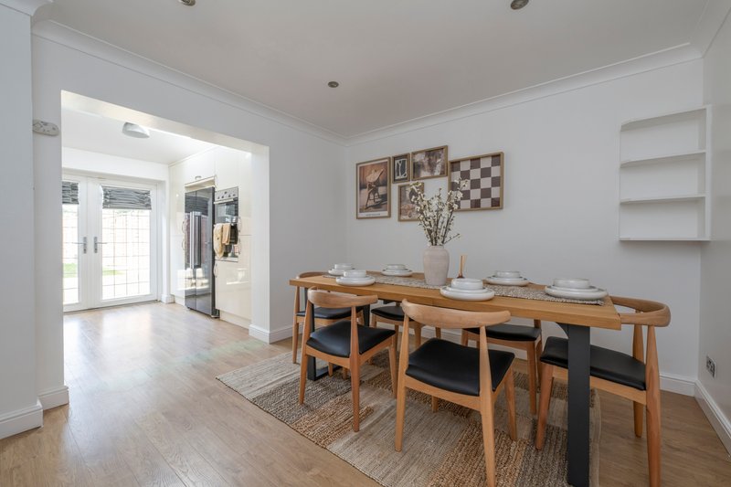 Bright dining room with wooden table, chairs, and wall art overlooking hallway
