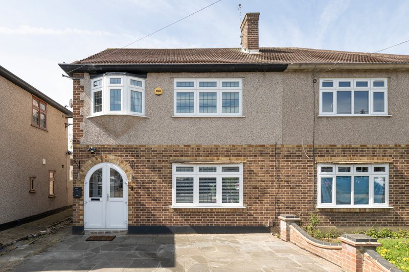 Semi-detached brick house with white-framed windows, white door, driveway and front garden