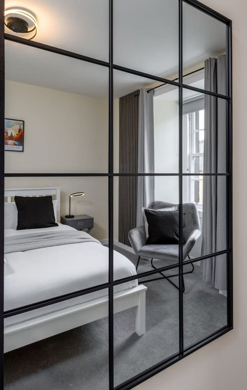 Modern bedroom with white bed, black accent pillow, and gridded glass partition door