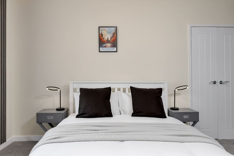 Modern bedroom with white bed, black pillows, bedside tables, lamps and framed wall art